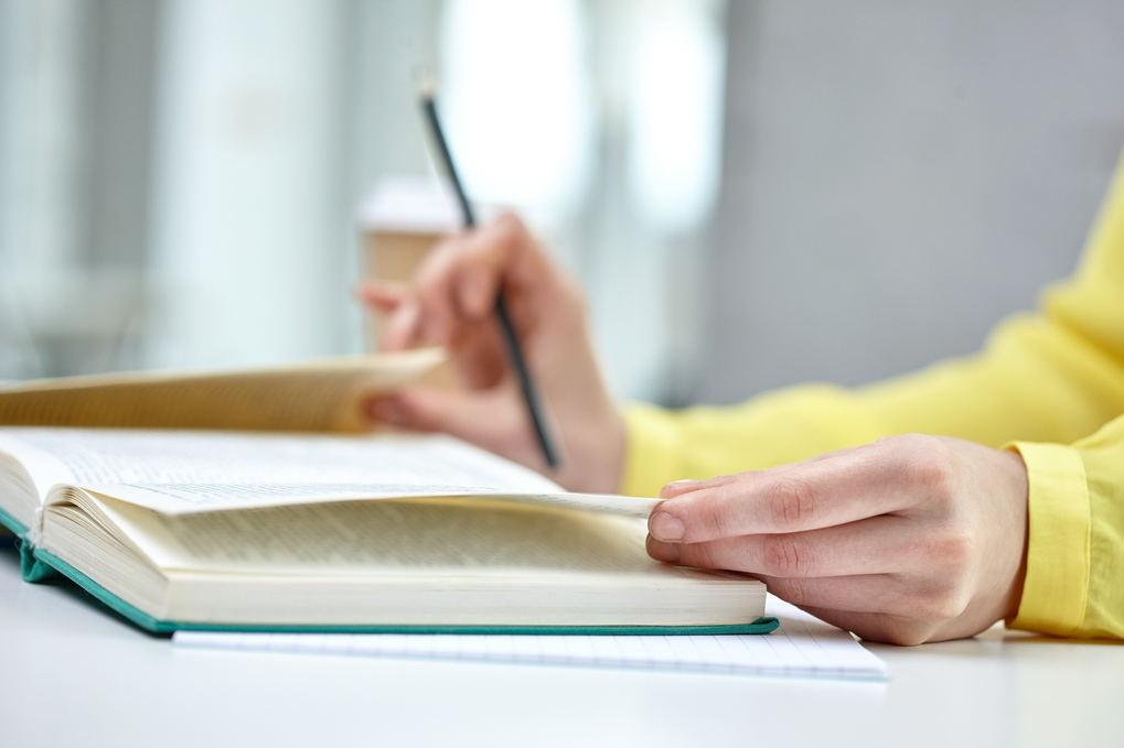 people and education concept - close up of female hands to book or textbook at school